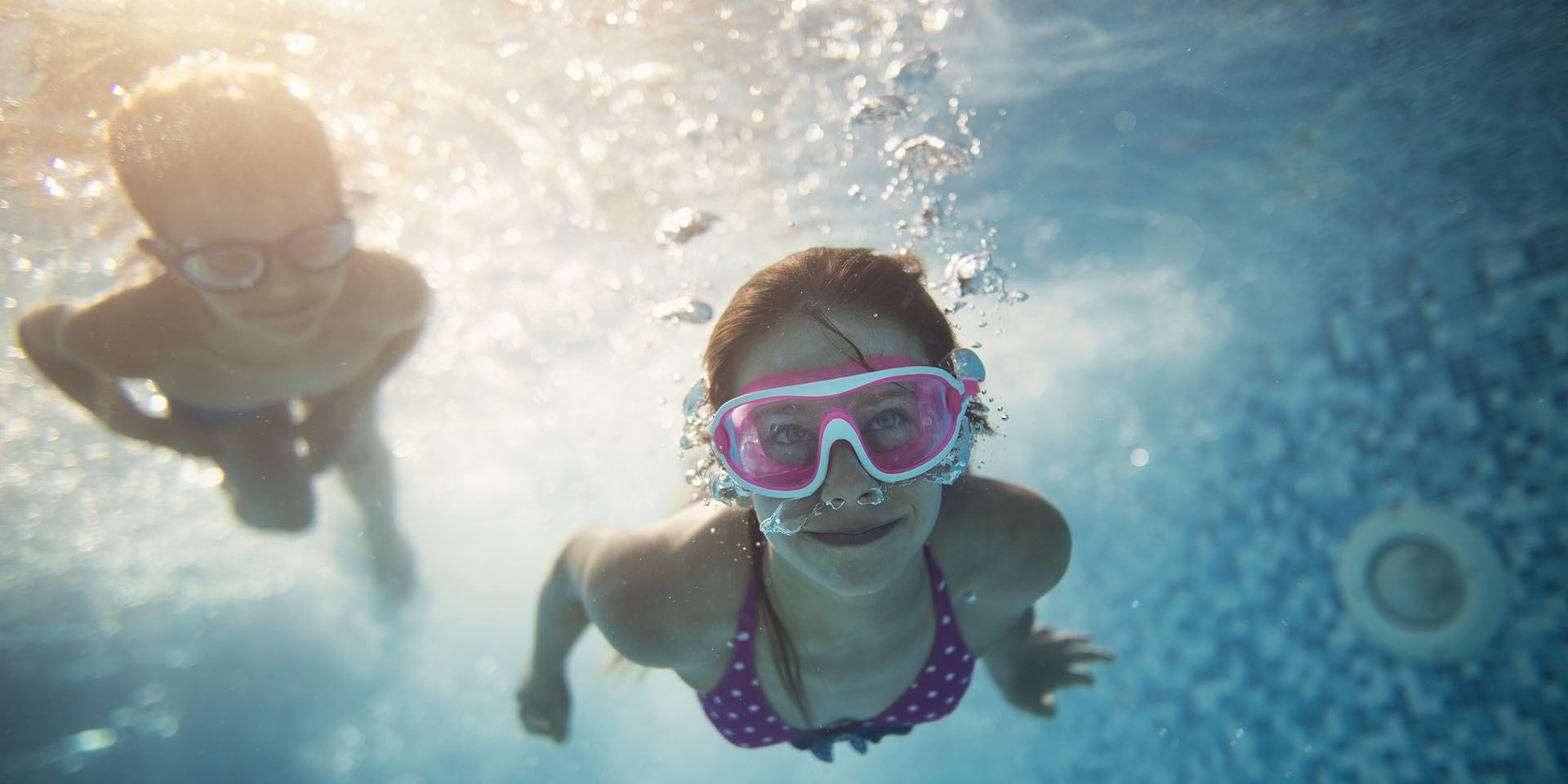 Piscina di un hotel con bambini in acqua, genitore vigile a bordo vasca